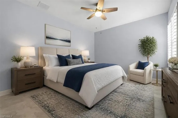 Well-lit bedroom featuring light blue walls and neutral tile flooring