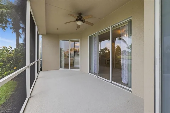 Spacious screened lanai featuring a ceiling fan, textured concrete flooring, and multiple sliding glass doors providing outdoor access