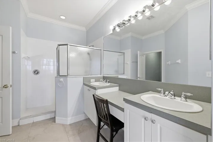 Master bathroom featuring a shower with a clear and frosted glass enclosure, dual vanity sinks with chrome fixtures, a long mirror, and recessed lighting
