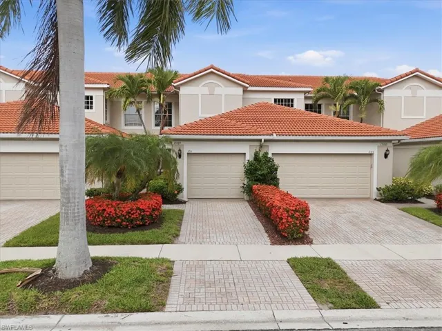 Mediterranean-style townhouse featuring a terracotta tile roof, two single-car garages, and paver driveways