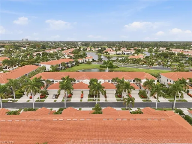 Aerial perspective showcasing a residential community with terracotta tile roofs, lush green landscaping, and multiple palm trees