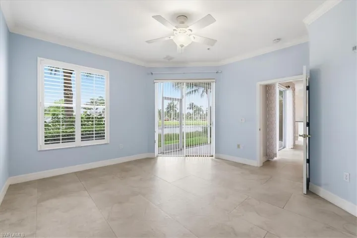 Spacious master bedroom featuring light blue walls, crown molding, and large format tile flooring