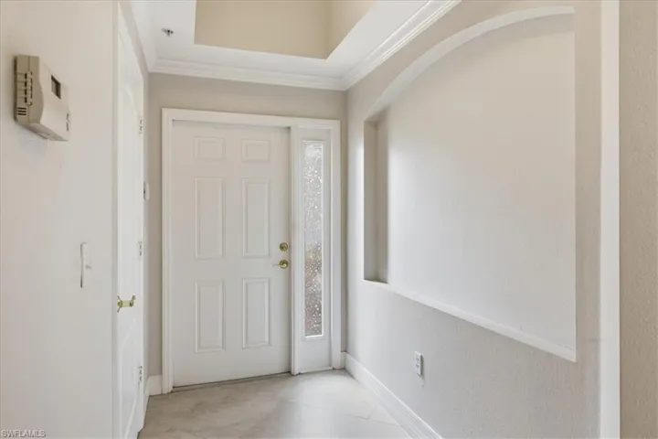Entryway featuring a paneled door with sidelight, crown molding, and an arched wall niche