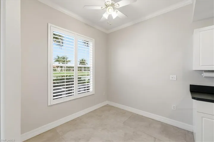 Room featuring a window with white louvered shutters, crown molding, a ceiling fan with integrated lighting, and neutral tone tile flooring