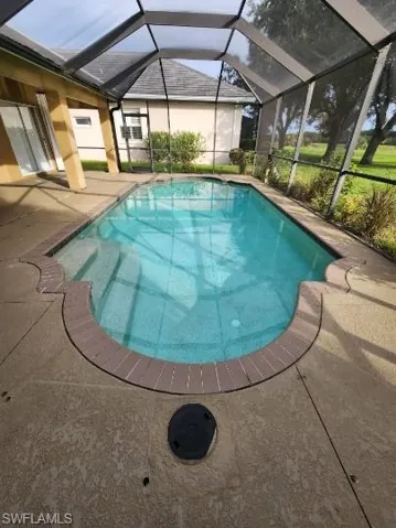 Swimming pool featuring a sunroom, a patio area, and a lanai