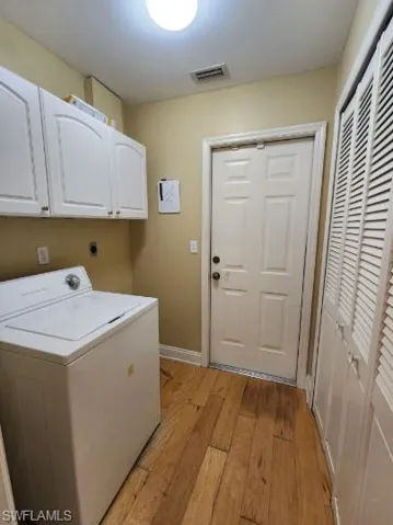 Laundry room with washer / dryer, light wood-style floors, and cabinet space