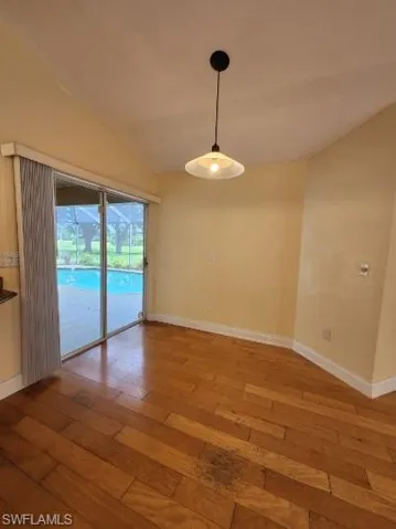 Unfurnished dining area featuring wood-type flooring and vaulted ceiling