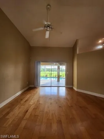 Spare room featuring wood finished floors, ceiling fan, and a high ceiling