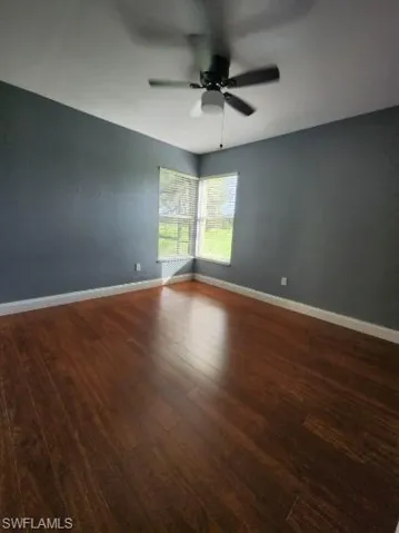 Spare room with dark wood-style flooring and a ceiling fan