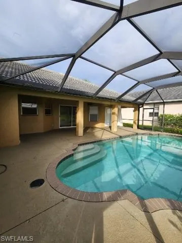 Swimming pool featuring a sunroom, a patio, and glass enclosure