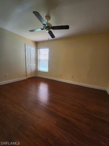 Empty room with dark wood-type flooring and a ceiling fan