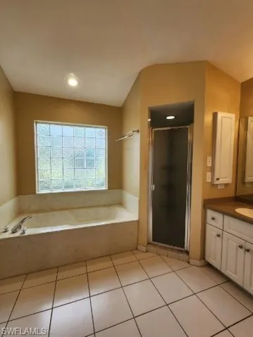 Full bath with a shower stall, vanity, a bath, and light tile patterned floors