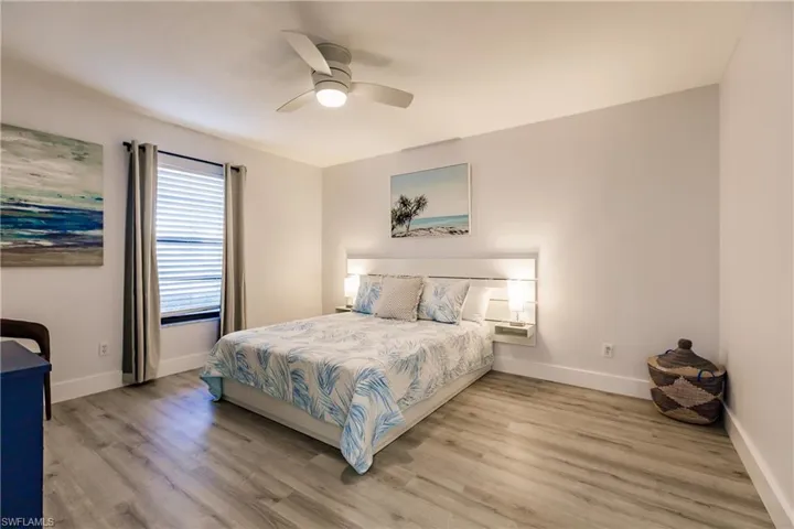 Bedroom with a ceiling fan, light wood-style flooring, and baseboards