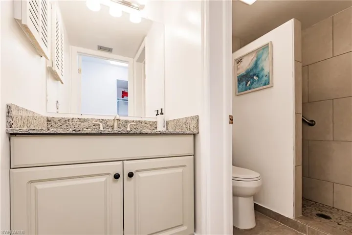 Bathroom featuring visible vents, toilet, tile patterned flooring, a tile shower, and vanity