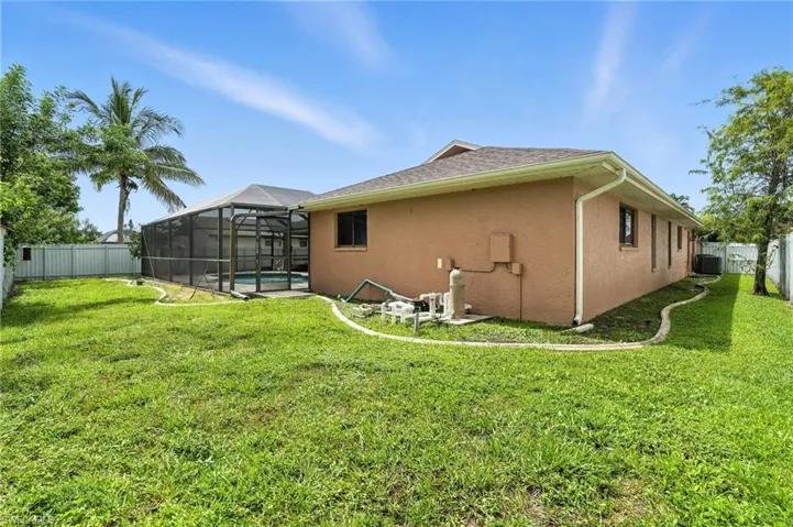 Rear view of property featuring a fenced backyard, stucco siding, glass enclosure, and roof with shingles