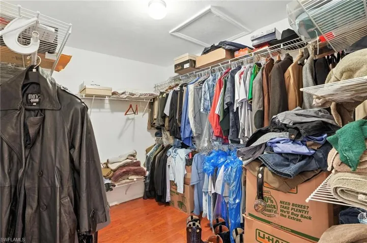 Walk in closet with attic access and wood finished floors