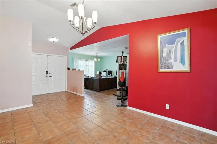 Foyer with a chandelier, vaulted ceiling, and light tile patterned floors