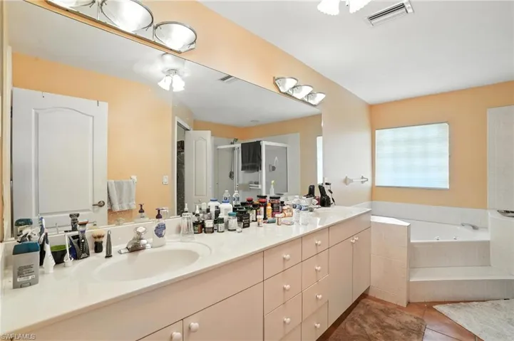 Bathroom featuring double vanity, tile patterned floors, a bath, and a stall shower