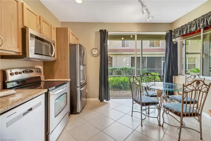 Kitchen with a healthy amount of sunlight, light tile floors, appliances with stainless steel finishes, and rail lighting