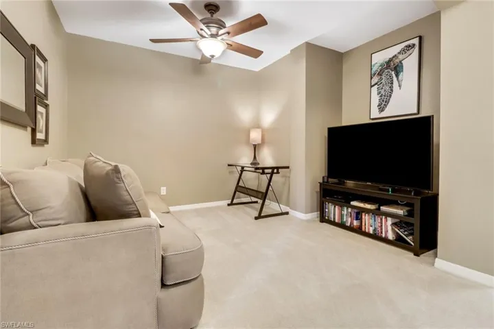 Carpeted living room featuring ceiling fan