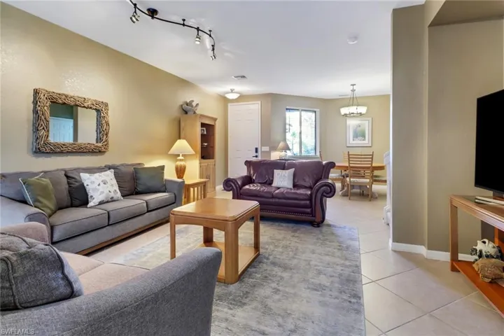 Living room with an inviting chandelier, light tile floors, and rail lighting