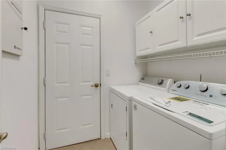 Laundry room with washer and dryer, cabinets, and light tile floors