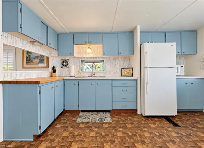 Kitchen featuring blue cabinetry, butcher block countertops, a double-basin stainless steel sink with a goose-neck faucet, and checkered-pattern flooring