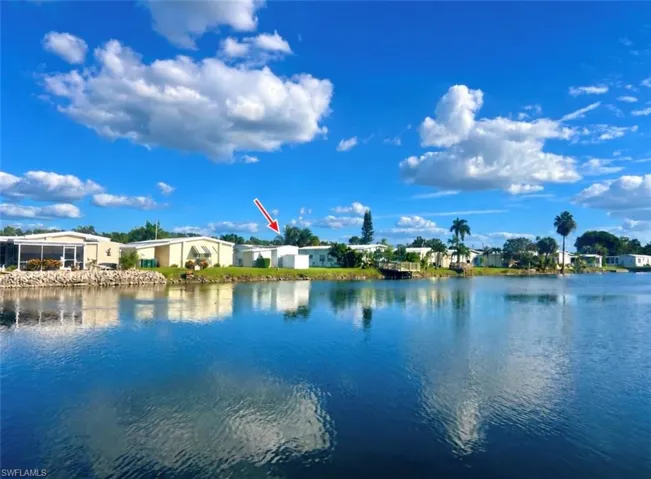 Waterfront property featuring shoreline access and mature palm trees