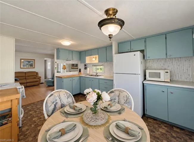 Kitchen featuring light blue cabinetry, solid surface countertops, patterned backsplash, integrated dual-basin sink, and decorative semi-flush mount lighting