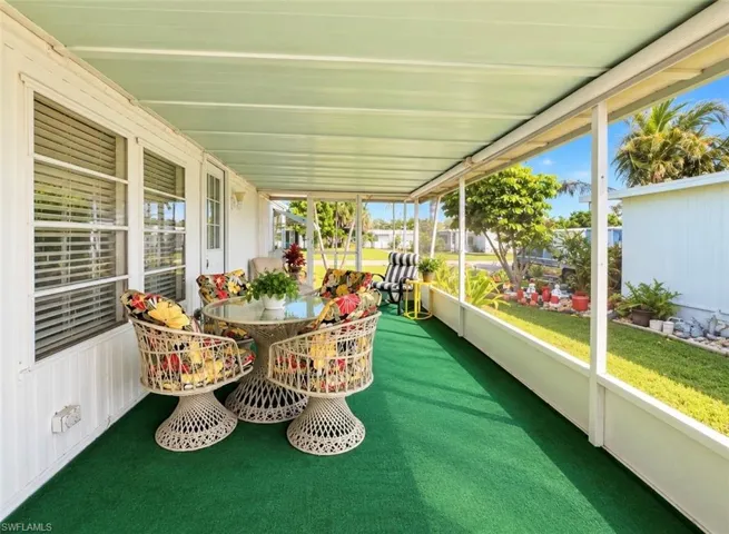 Screened-in porch featuring a solid roof covering, full-length window screens, and green outdoor carpeting
