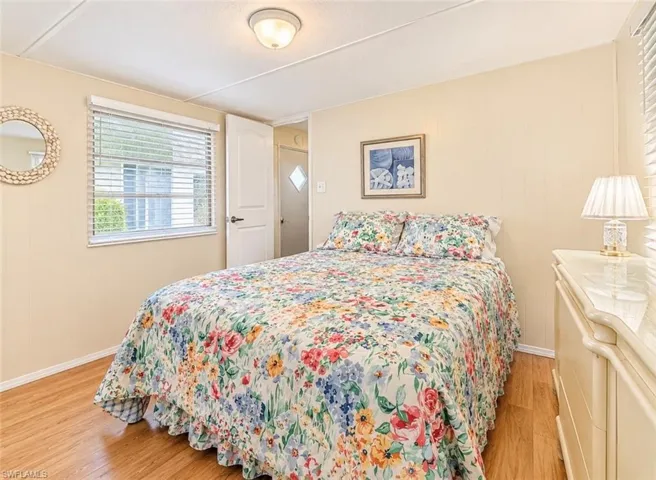 Room featuring wood-finish flooring, paneled walls, a flush-mount ceiling light fixture, and horizontal window blinds