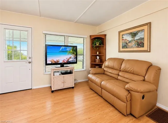 Interior room featuring wood-finish flooring, built-in wooden corner shelving, and large dual-pane windows