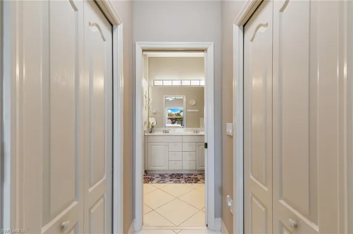 Bathroom with double vanity, light tile patterned floors, and a closet