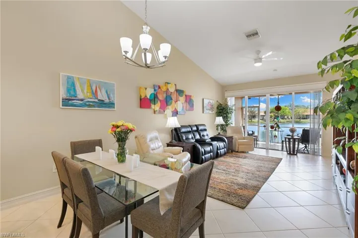 Dining area featuring a ceiling fan, vaulted ceiling, a water view, light tile patterned floors, and suspended lighting