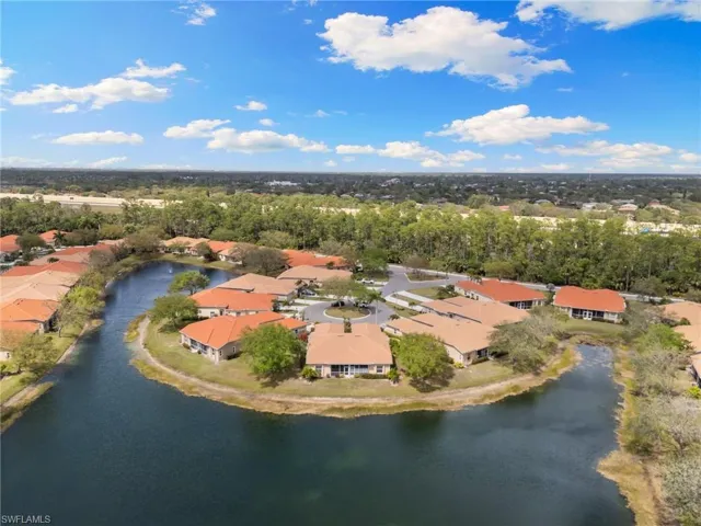 Aerial view of residential area with a nearby body of water and a tree filled landscape