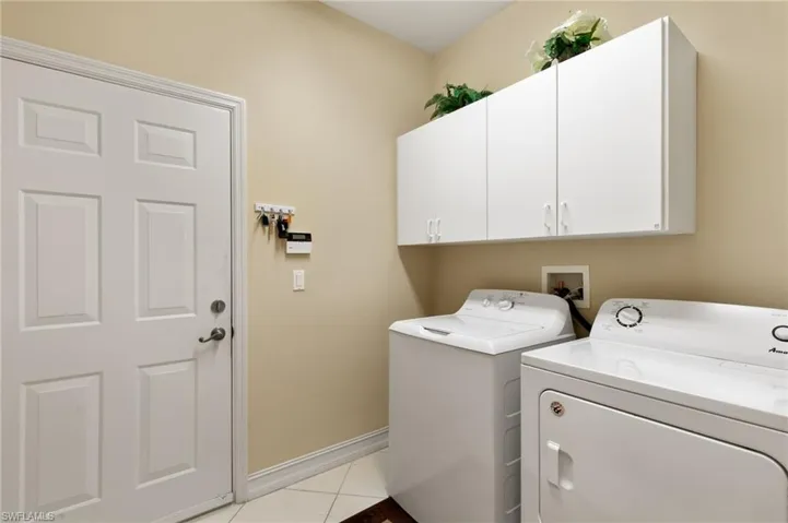 Laundry room featuring cabinet space, light tile patterned floors, and separate washer and dryer