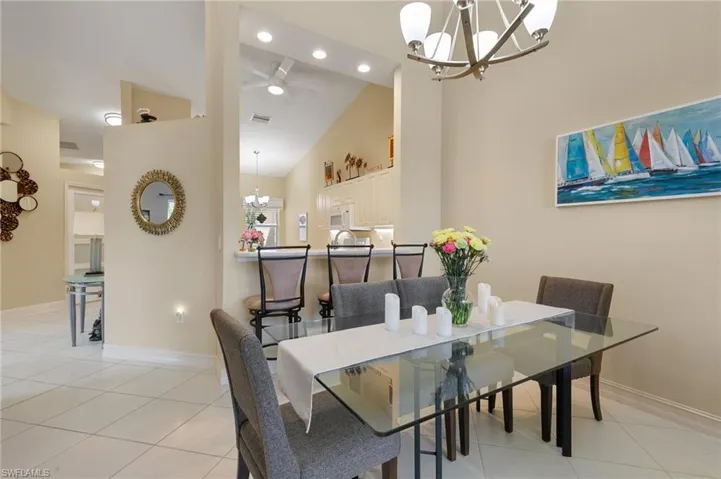 Dining room with a chandelier, a ceiling fan, light tile patterned flooring, and lofted ceiling