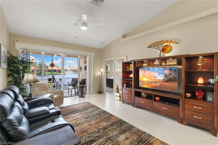 Living room with a ceiling fan, light tile patterned floors, and lofted ceiling
