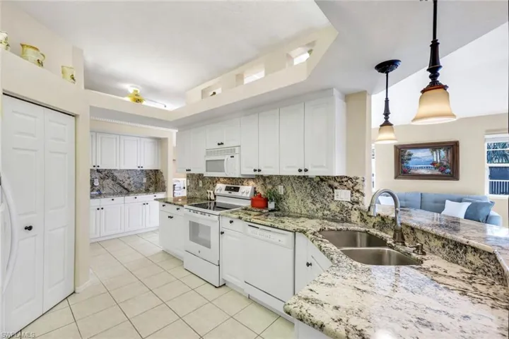 (Virtual wall color change) Large kitchen with granite countertops, bar seating, plenty of cabinetry for storage and large pantry.