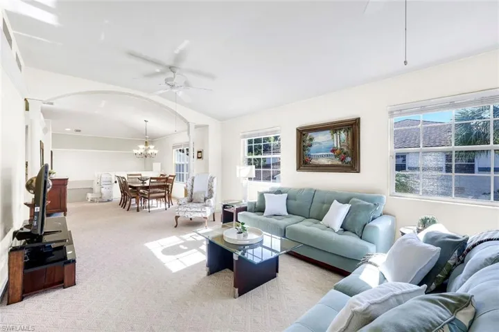 (Virtual wall color change) Spacious living room with lots of natural light, dining area, and carpeted flooring.