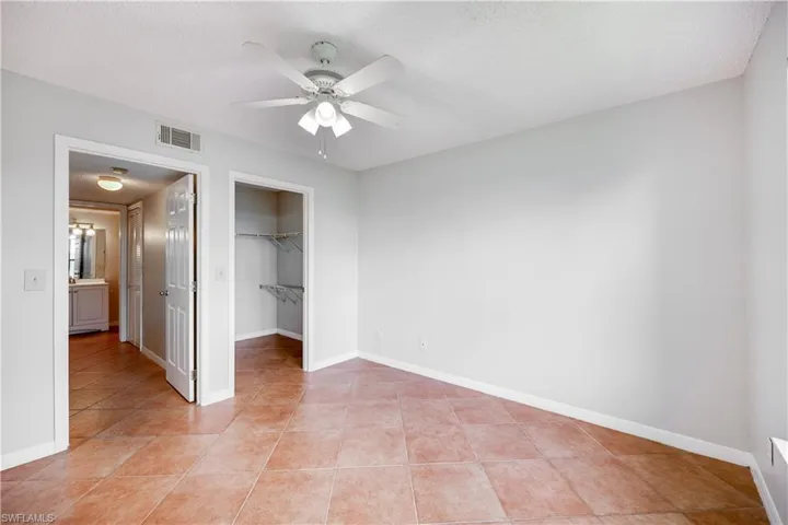 Unfurnished bedroom featuring a closet, a textured ceiling, ceiling fan, and light tile patterned floors