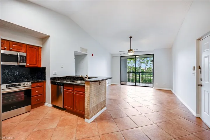 Kitchen with lofted ceiling, light tile patterned floors, ceiling fan, stainless steel appliances, and sink