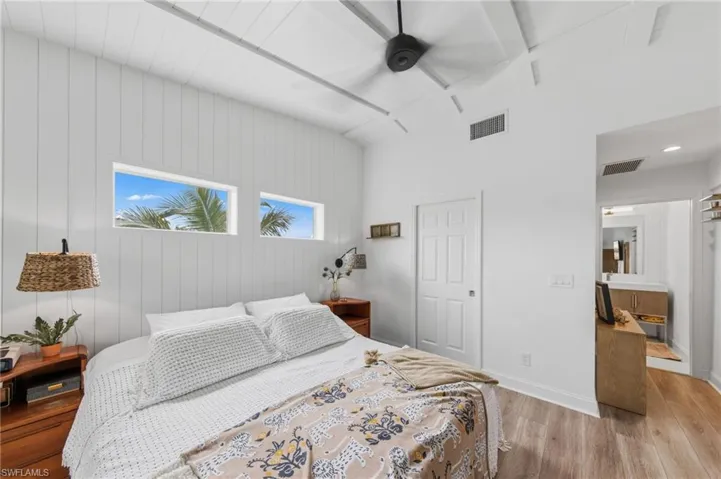 Bedroom with light wood finished floors, ceiling fan, and wooden walls