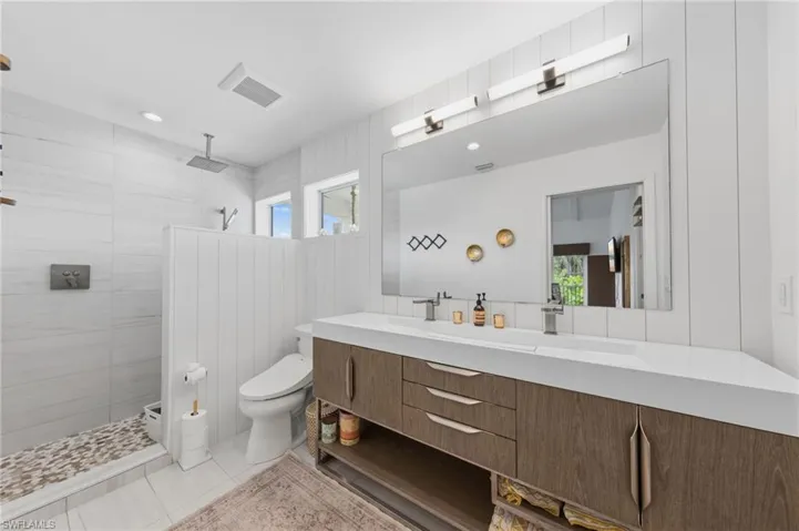 Full bath featuring vanity, a walk in shower, plenty of natural light, and light tile patterned floors