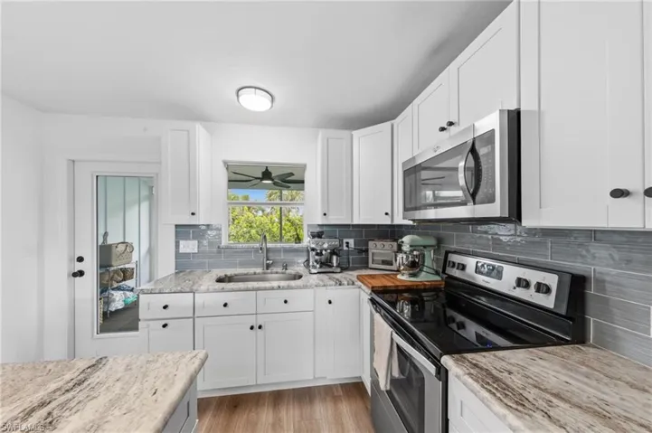 Kitchen featuring stainless steel appliances, white cabinetry, and light wood-style flooring