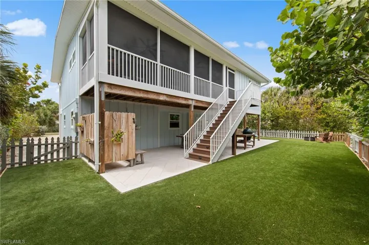 Rear view of property with a patio area, a sunroom, a fenced backyard, and board and batten siding