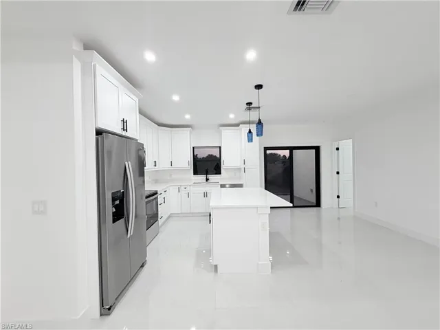 Kitchen featuring appliances with stainless steel finishes, white cabinetry, a kitchen island, hanging light fixtures, and recessed lighting