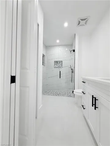 Bathroom with vanity, a marble finish shower, and recessed lighting