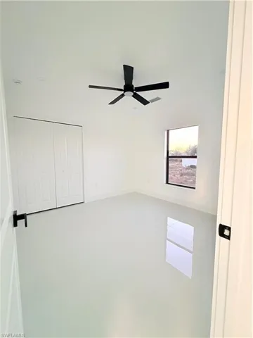 Unfurnished bedroom featuring finished concrete flooring, a ceiling fan, and a closet