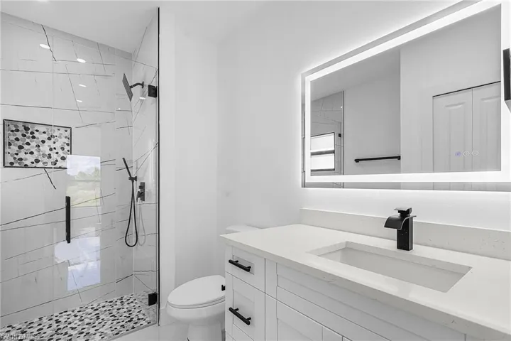 Full bath featuring vanity and a marble finish shower